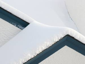 Post Falls home with a snow-covered roof, showcasing effective winter maintenance to avoid emergency repair calls.