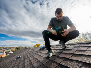 Professional roofing contractor in Post Falls inspecting a roof for wind damage.