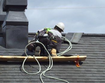 Roofer performing emergency roof repairs on storm-damaged roof in Post Falls