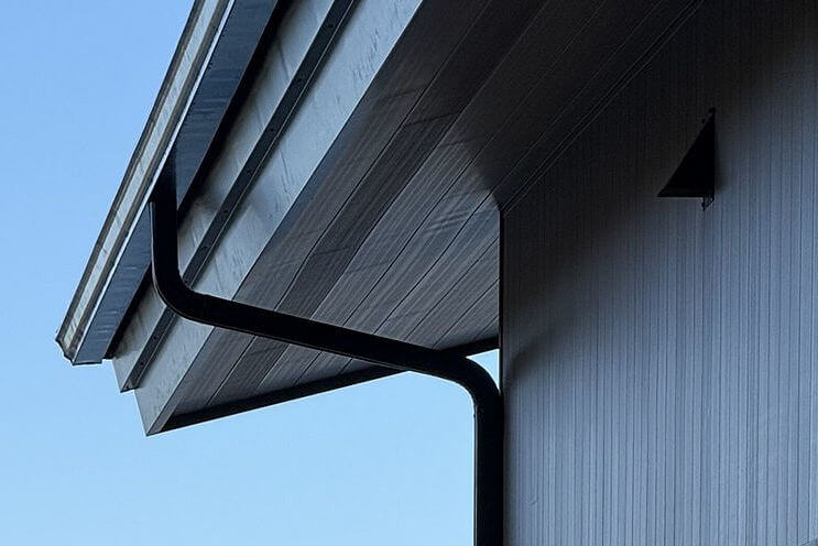 Close up of a black colored gutter on residential home by a lake