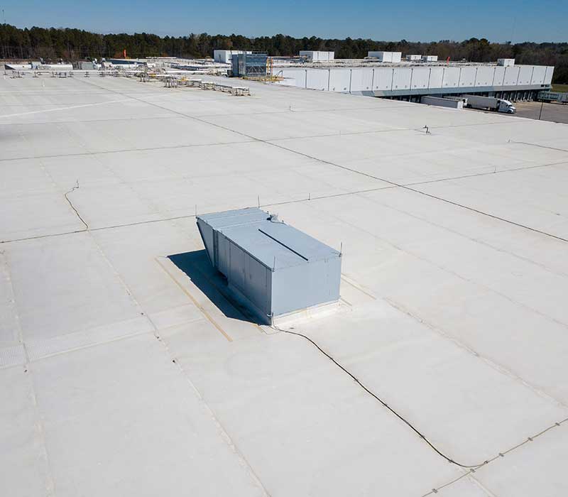 Top view of a large warehouse roof with an AC unit on top